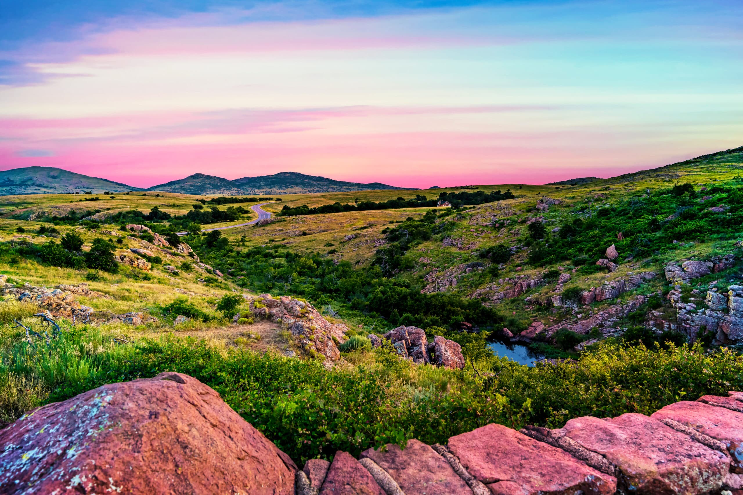 The beautiful green vibrant hills glowing in the sunset under a pastel colored sky at Wichita Mountains Wildlife Refuge near Lawton, Oklahoma, USA