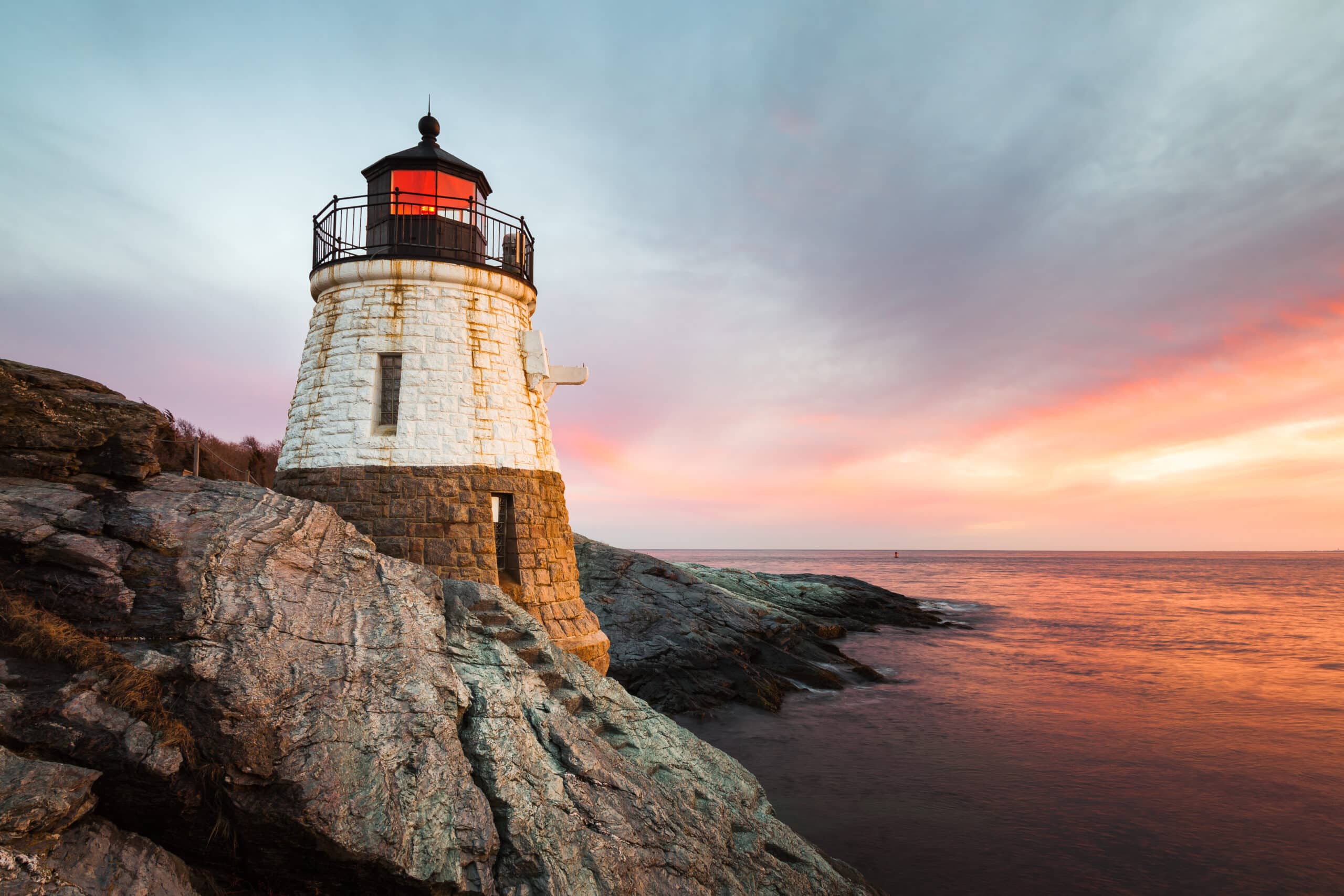 Small, white, granite built Castle Hill Lighthouse sits on the rocky coastline of Newport, Rhode Island on the Atlantic coast of New England