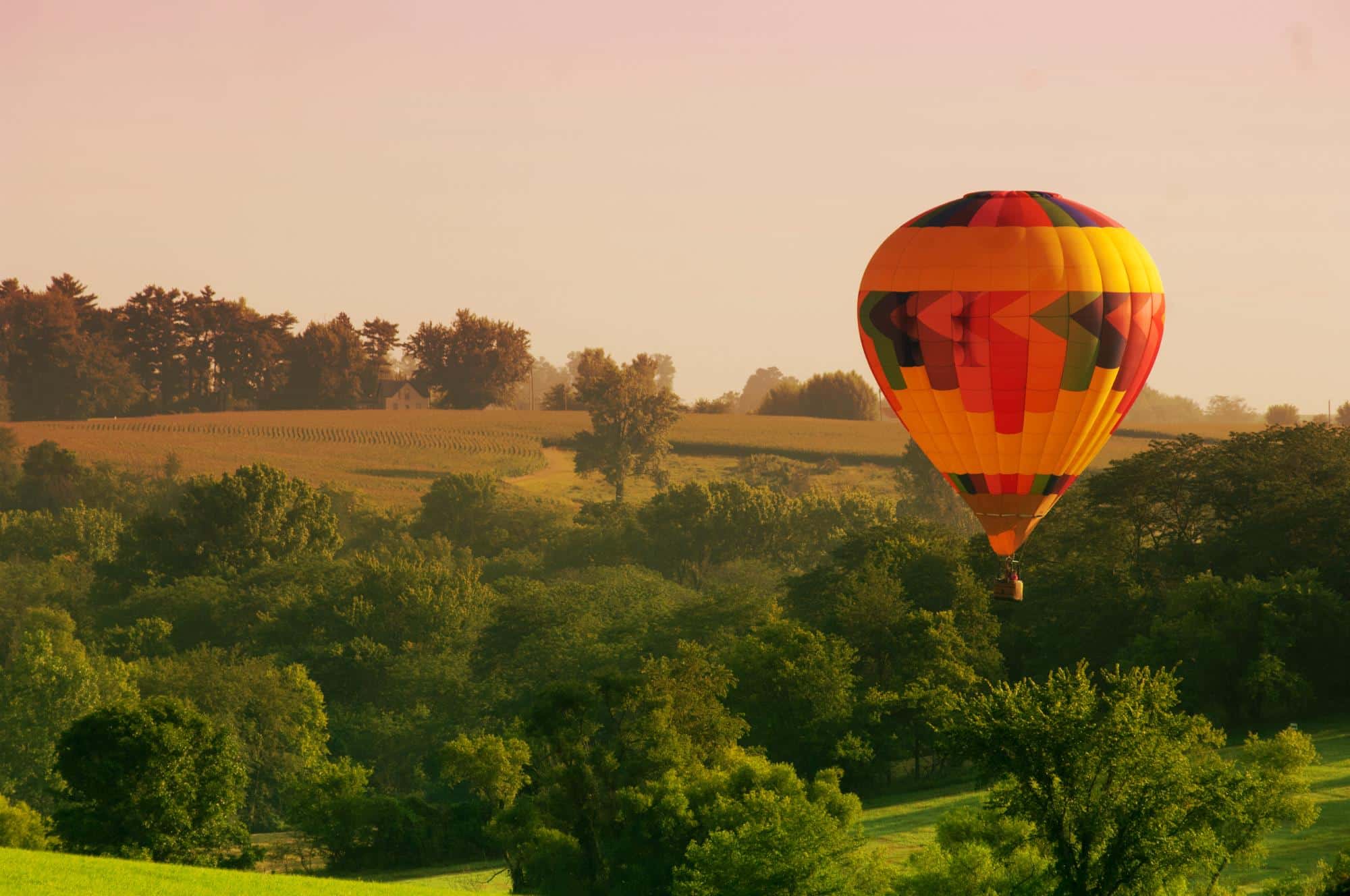 A hot air balloon floats above an Iowa rural landscape