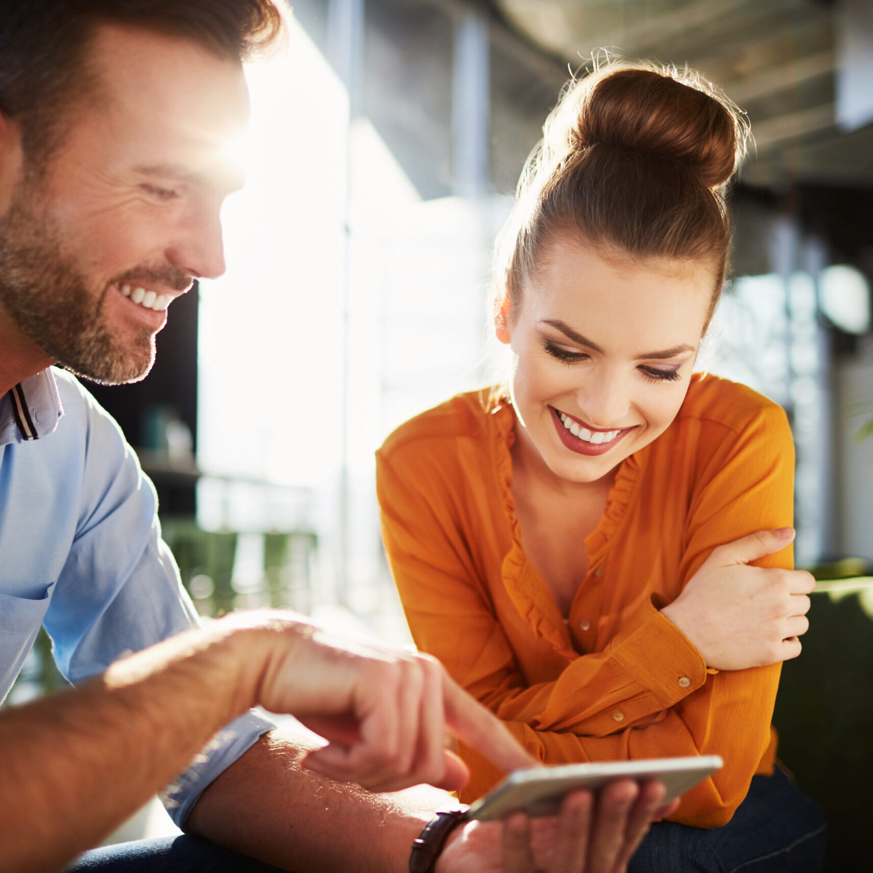 Young couple in modern cafe looking at smartphone